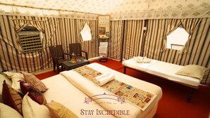 Une chambre d’hôtel avec un grand lit, une table de chevet, une chaise et une petite table avec une lampe.