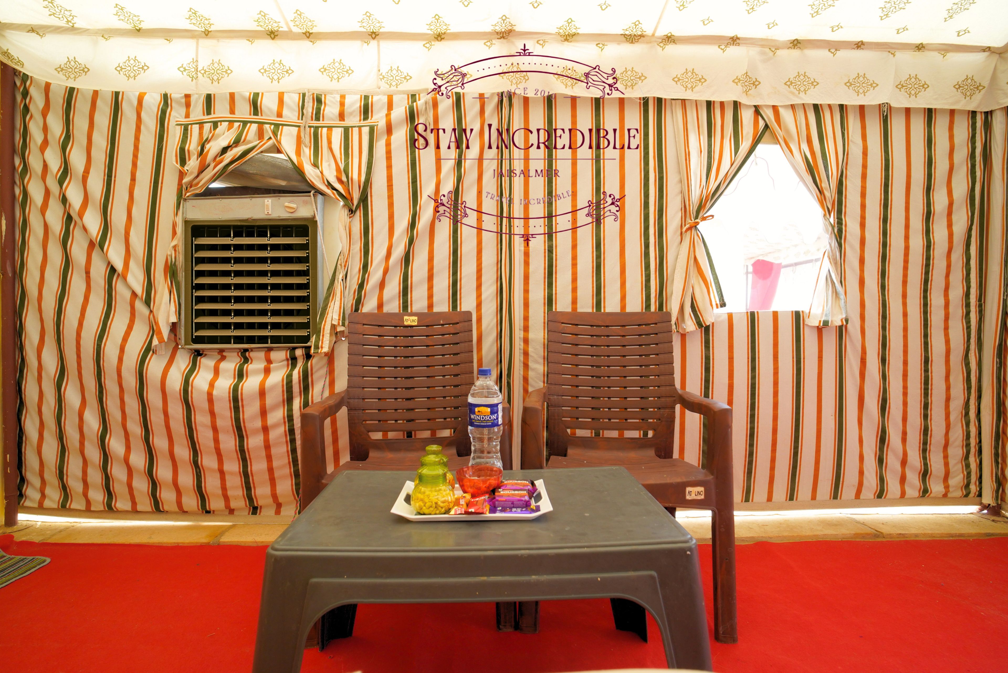 A room with striped curtains, a table with snacks, and two wooden chairs.