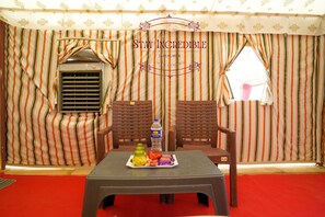 A room with striped curtains, a table with snacks, and two wooden chairs. - Stay Incredible Camp (Jaisalmer)