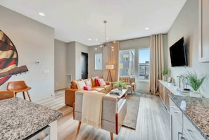 A modern living room with a sofa, coffee table, and a TV mounted on the wall. - Nashville music-themed home with game room, sleeps 12 near Nissan Stadium (Nashville)