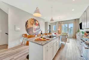 A modern kitchen with a central island, pendant lighting, and a large window providing natural light.