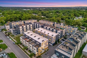 A modern apartment complex with multiple buildings, a central courtyard, and a view of the surrounding greenery. - Nashville rooftop fire pit house with ping pong, sleeps 12 near Broadway (Nashville)