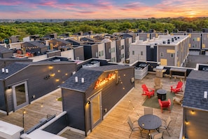 A rooftop terrace with multiple levels, outdoor seating, and a view of the surrounding greenery.