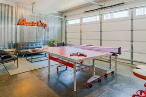 Une table de ping-pong dans une pièce spacieuse, avec un mur en métal ondulé et une enseigne indiquant « Music City ».