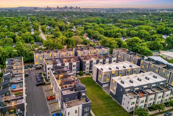 A modern apartment complex with multiple buildings, a parking area, and surrounding greenery. - Nashville rooftop fire pit house with ping pong, sleeps 12 near Broadway (Nashville)
