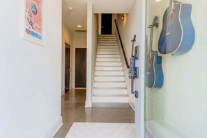 Un escalier muni d’une rampe, un tableau encadré accroché au mur et des guitares appuyées contre le mur.