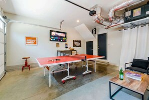 Une table de ping-pong dans une pièce où se trouvent un téléviseur, une carte et une porte.