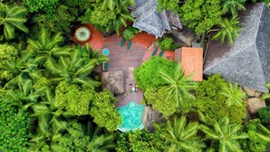An aerial view of a resort with a swimming pool, lounge area, and multiple buildings surrounded by dense tropical vegetation. - Niva Labriz Seychelles (Silhouette Island)