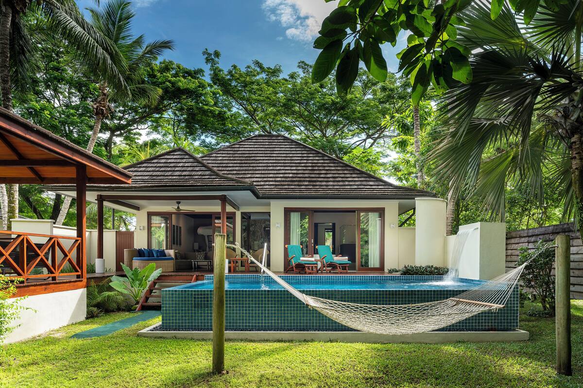 Ein Haus mit Swimmingpool, einer Hängematte und einer Terrasse mit Stühlen und einem Tisch.