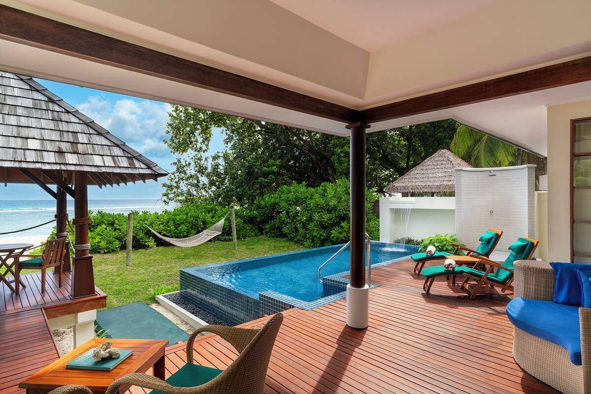 Eine Holzterrasse mit Pool, Liegestühlen und einer Hängematte.