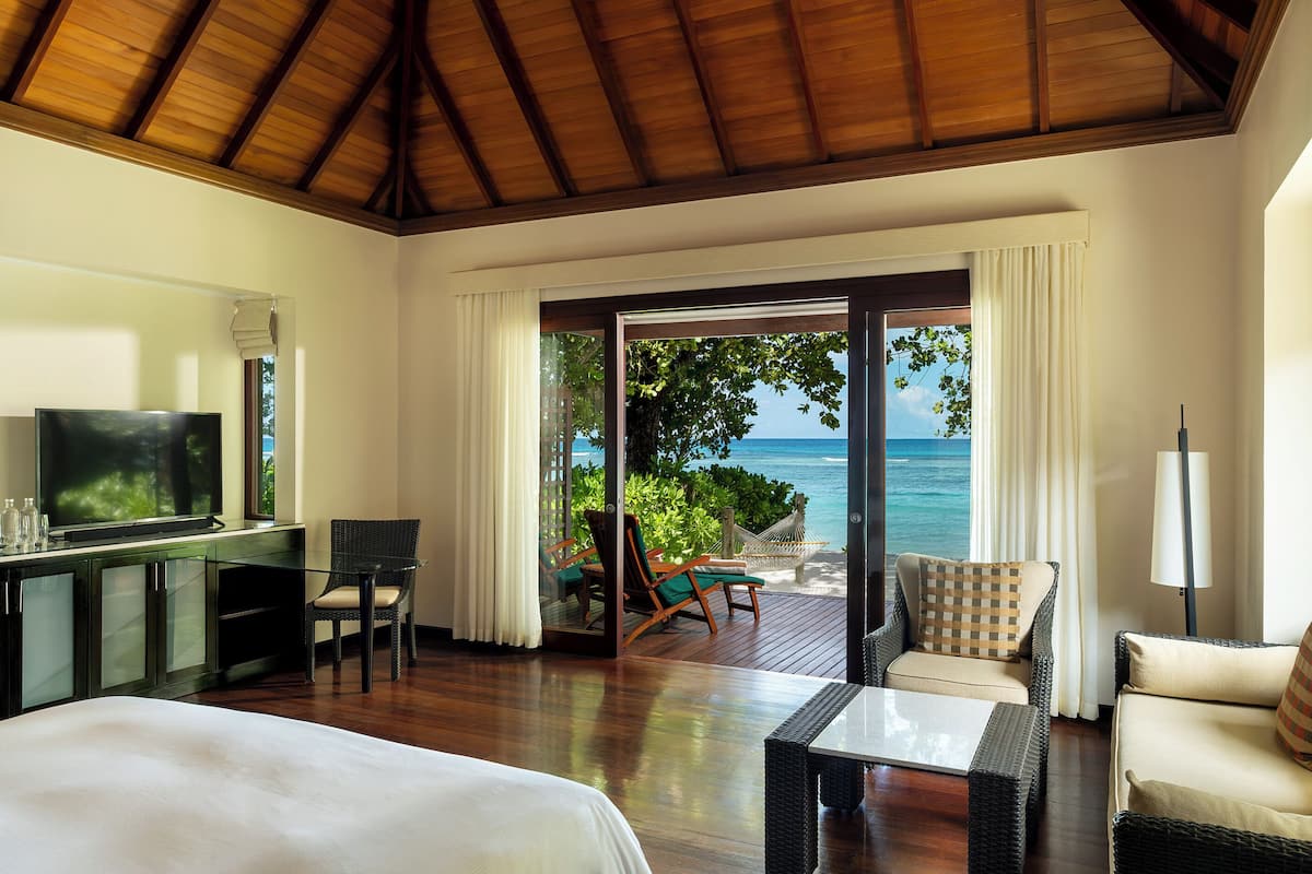 Ein Hotelzimmer mit Holzboden, einem Bett, einem Fernseher, einem Schreibtisch und Blick aufs Meer.