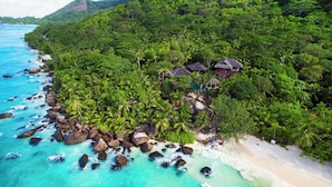 A tropical beach resort with a rocky shoreline, clear turquoise waters, and lush greenery. - Niva Labriz Seychelles (Silhouette Island)