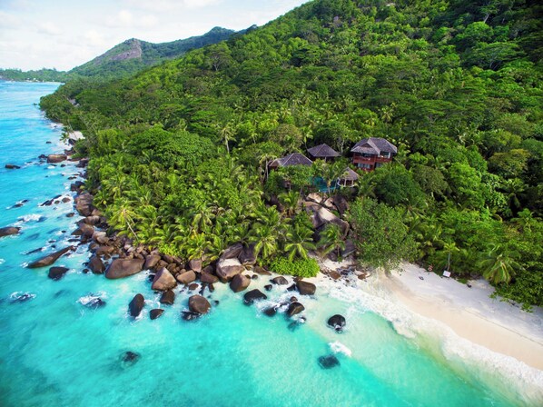 A tropical beach resort with a rocky shoreline, clear turquoise waters, and lush greenery. - Niva Labriz Seychelles (Silhouette Island)