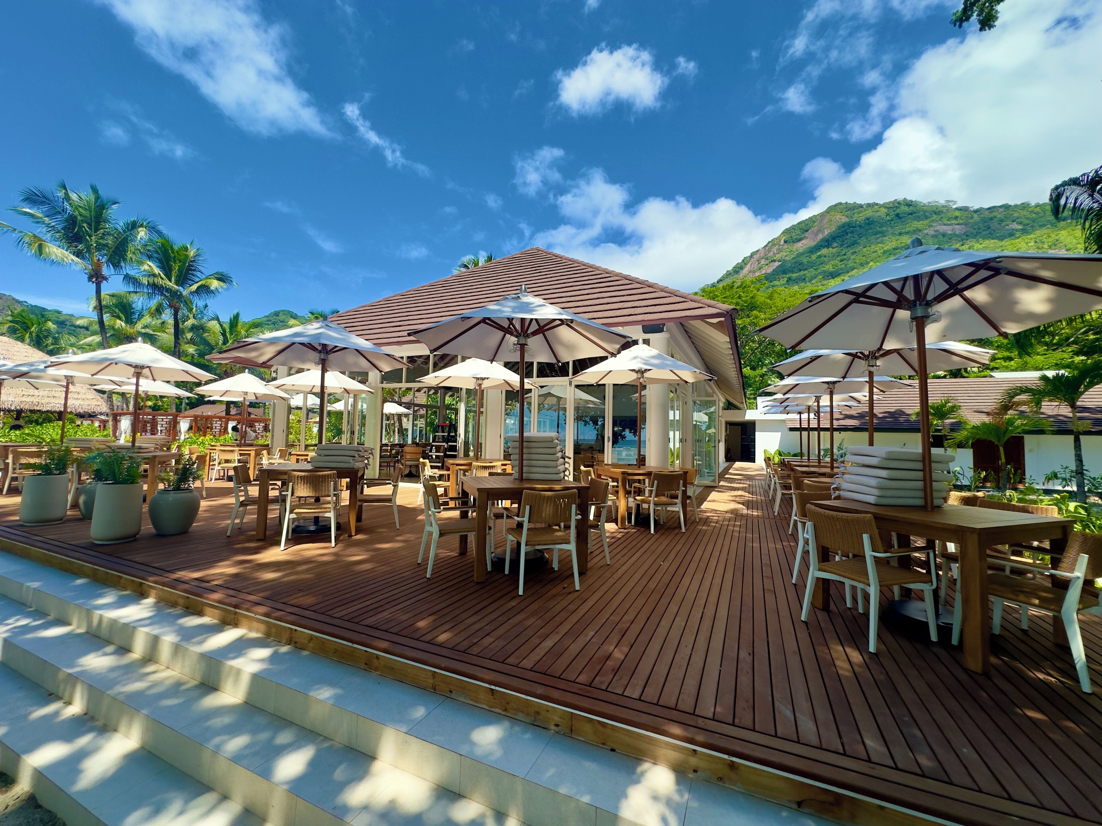 A wooden deck with outdoor seating, umbrellas, and potted plants.