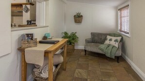 Un salon chaleureux avec une table en bois, un canapé et une fenêtre équipée de stores.