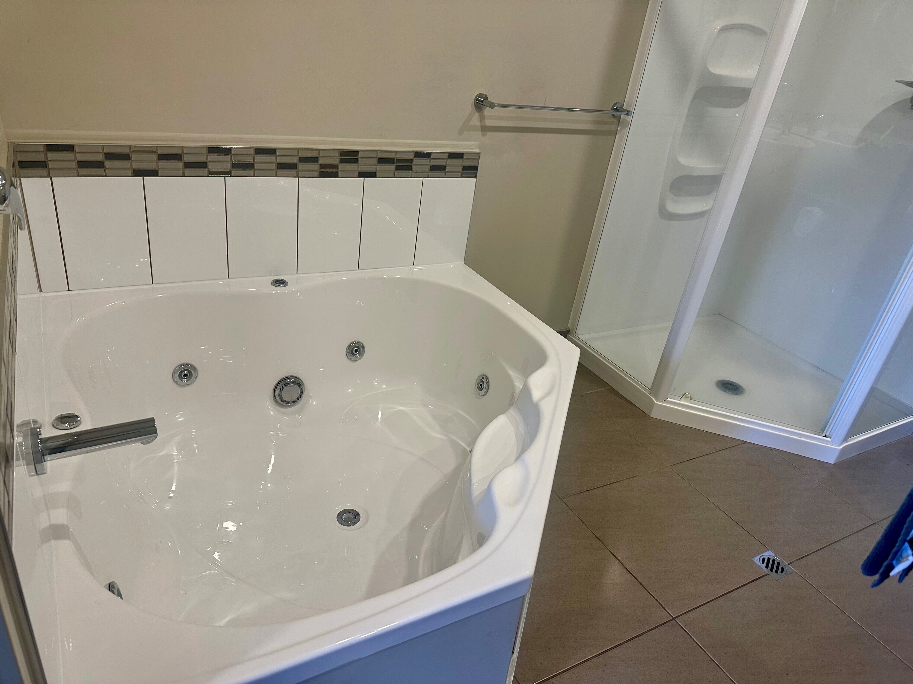 Une salle de bain dotée d’une grande baignoire, d’un espace douche et d’un sol carrelé.