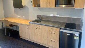 A modern kitchen with wooden cabinets, a stainless steel refrigerator, a microwave, and a sink.