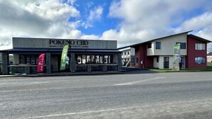 A building with a sign reading "POKENO CBD" and a green "OPEN" sign.
