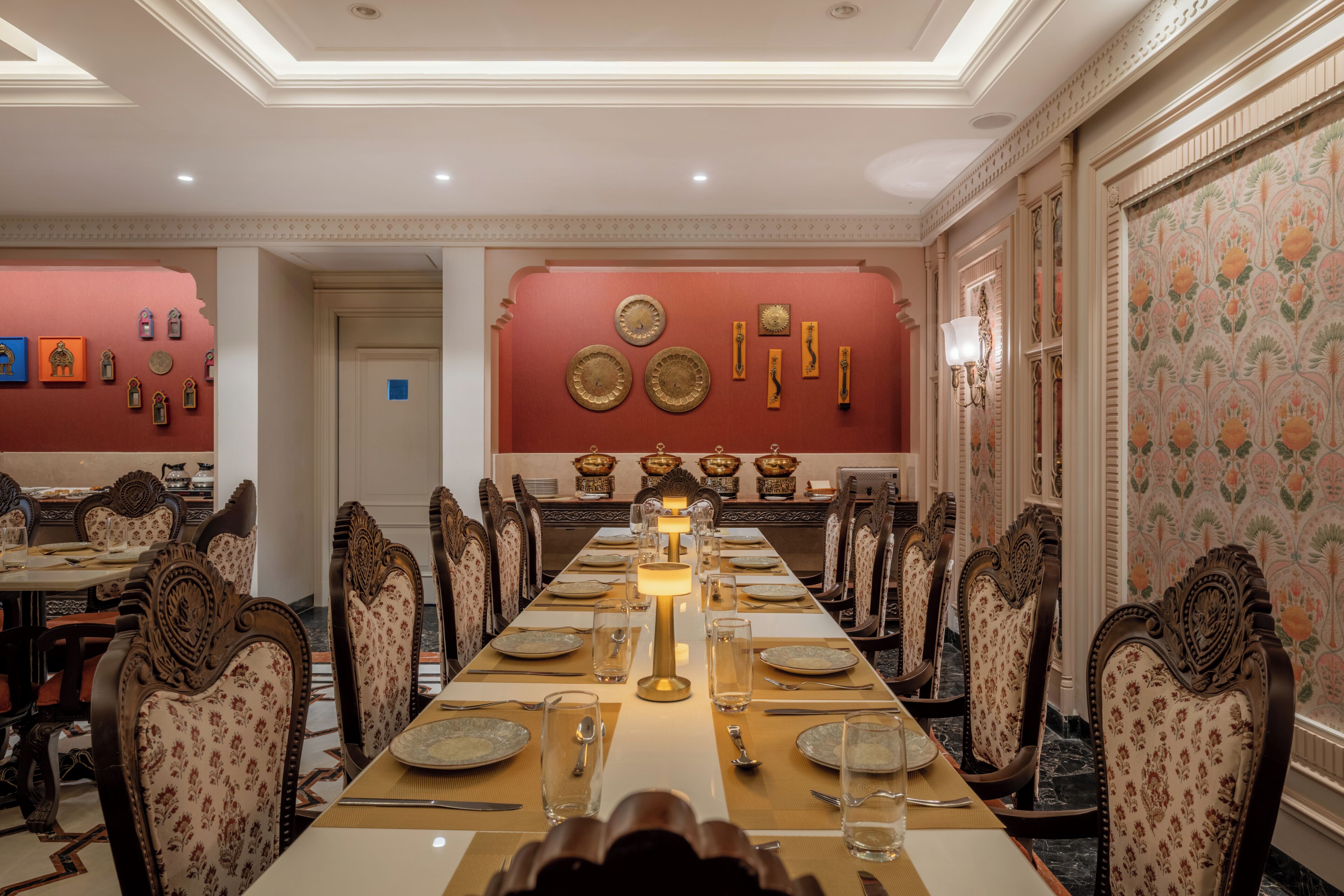 A formal dining room with a long table set for a meal, surrounded by ornate chairs.