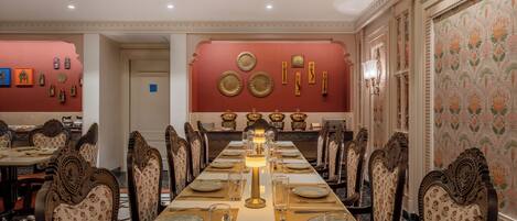 A formal dining room with a long table set for a meal, surrounded by ornate chairs.