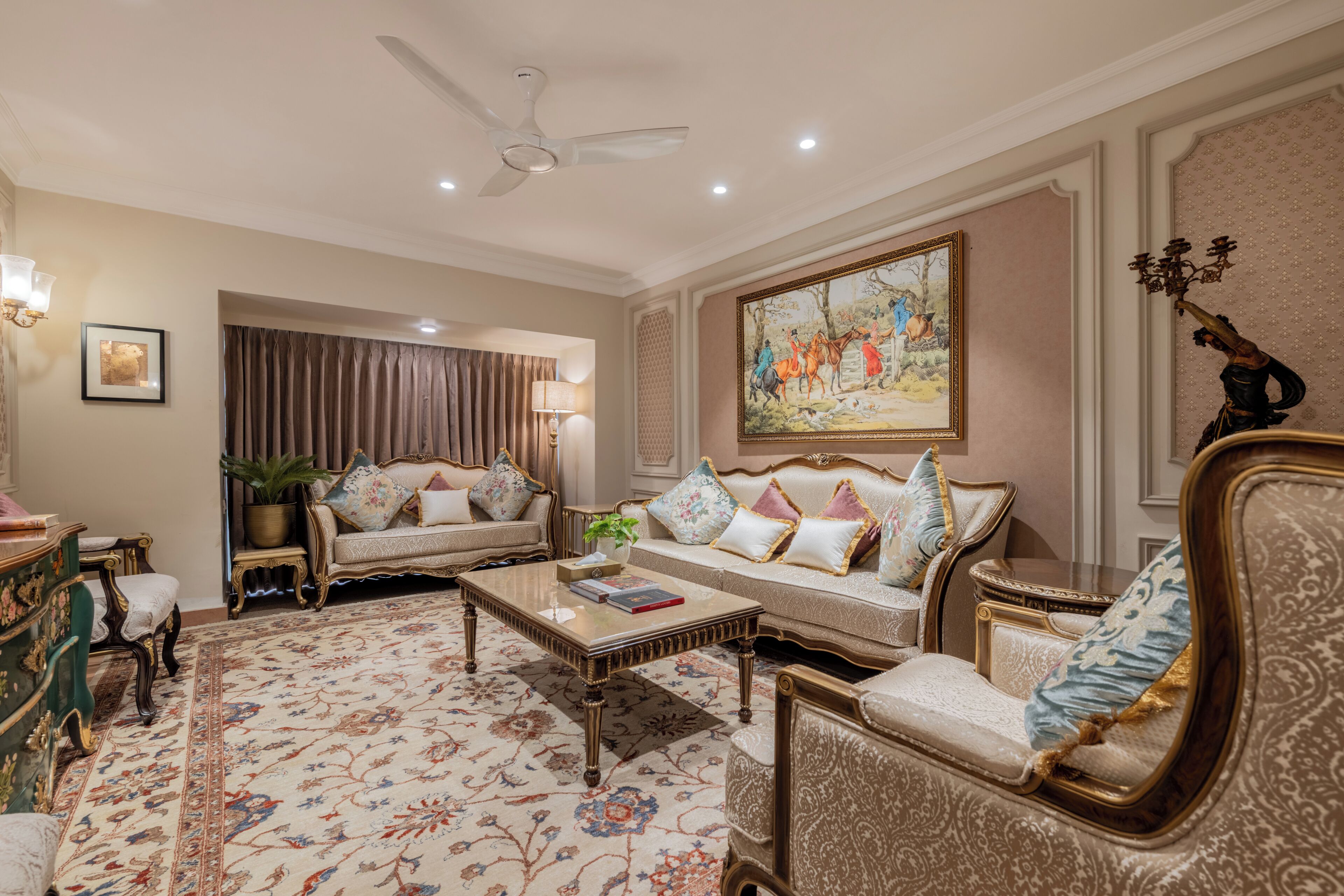 A spacious living room with a high ceiling, a ceiling fan, a large painting, and a chandelier.