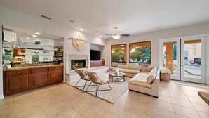 A spacious living area with a sofa, a coffee table, and a fireplace. - Indio Estate | Pool, Putting Green, Sleeps 12 (Indio)