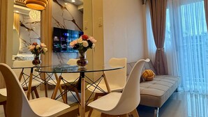 Un comedor moderno con mesa de vidrio, sillas de madera e iluminación colgante.
