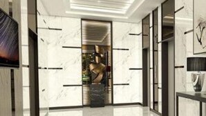 Un moderno vestíbulo de hotel con piso de mármol, televisor de pantalla plana y una mesa de recepción.