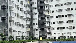 Un edificio residencial de gran altura con varios balcones y una piscina en primer plano.