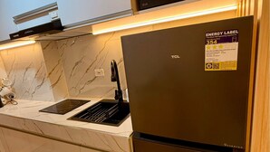 Una cocina moderna con un refrigerador negro, un horno empotrado y una encimera de mármol.