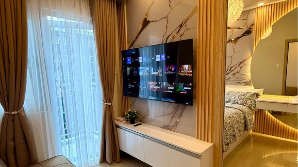 Un dormitorio moderno con televisor montado en la pared, un sofá, una cama y un tocador.