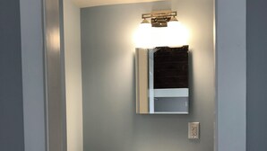 Une salle de bain avec un meuble-lavabo blanc, un miroir et un luminaire au plafond.