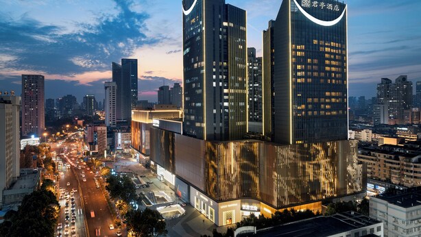 A modern hotel with a prominent glass facade and two tall towers. - SSAW Boutique Hotel Hefei (Hefei)