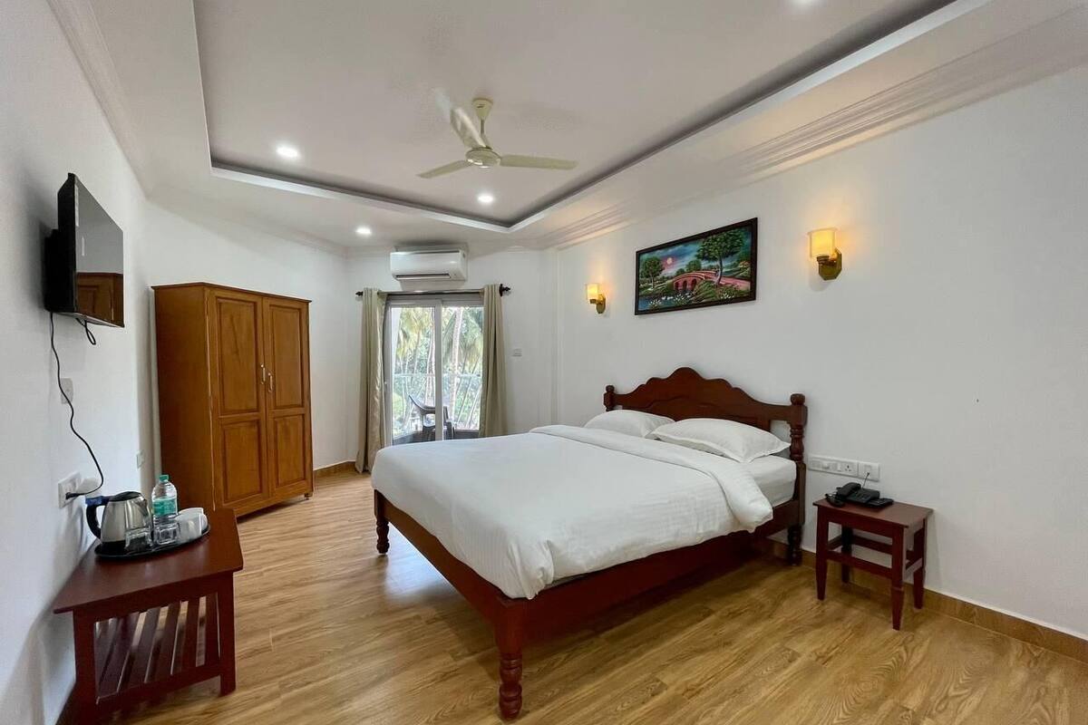 Un dormitorio con cama de madera, ventilador de techo, televisor montado en la pared y armario de madera.