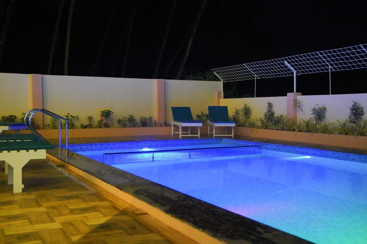 A swimming pool with a wooden deck, two lounge chairs, and a metal staircase leading into the pool.