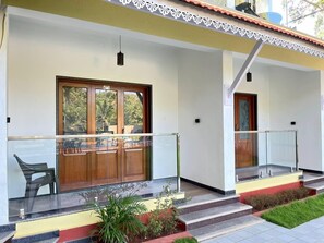 A modern building with a glass balcony, a wooden door, and a small outdoor seating area. - Palm Paradise Resort (Querim)