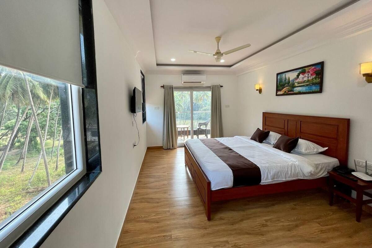 Un dormitorio con cama, ventilador de techo, un cuadro y vistas a través de una ventana.