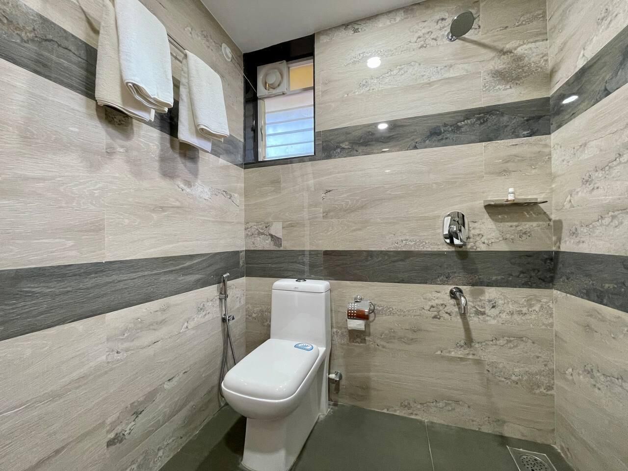 A bathroom with a toilet, shower, and towel rack.