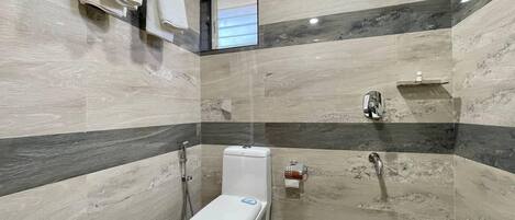 A bathroom with a toilet, shower, and towel rack.