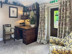 A room with a wooden desk, a chair, a bookshelf, a potted plant, and a window with curtains. - Gillhead Farm Cottage (Matterdale End)