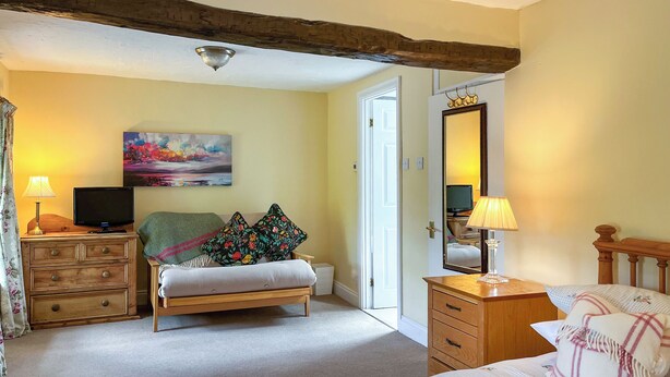 A bedroom with a bed, a dresser, a television, a painting, and a mirror. - Gillhead Farm Cottage (Matterdale End)