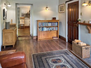 A room with a wooden floor, a bookshelf, a leather chair, a rug, and a door.