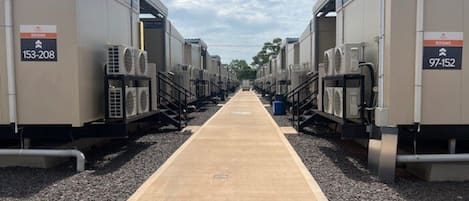 A row of industrial-style buildings with air conditioning units, labeled with room numbers 153-208 and 97-152.