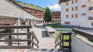 Un pasillo de hotel con barandillas de madera, un camino pavimentado y una vista de la montaña al fondo.