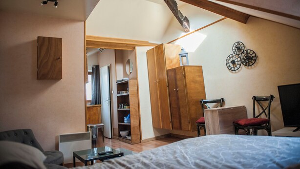 A bedroom with a bed, a desk, a chair, a wardrobe, and a mirror.