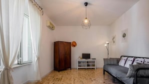A living room with a sofa, TV, cabinet, and a patterned floor.