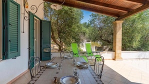 An outdoor dining area with a tiled floor, green chairs, and a table set for two.