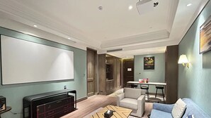 A modern living room with a flat-screen TV, a coffee table, a sofa, and a dining area with a table and chairs. - SSAW Boutique Hotel Qingdao Chuangzhi (Qingdao)