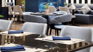 A modern dining area with round tables, chairs, and a blue accent wall. - SSAW Boutique Hotel Qingdao Chuangzhi (Qingdao)