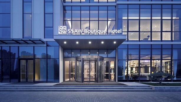 The exterior of the SSAW Boutique Hotel with a revolving door entrance and large windows. - SSAW Boutique Hotel Qingdao Chuangzhi (Qingdao)